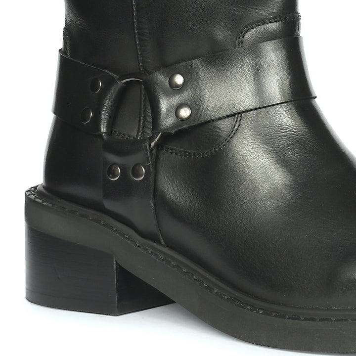 Close-up of the O-ring harness strap on the black leather high ankle boot with metal rivets