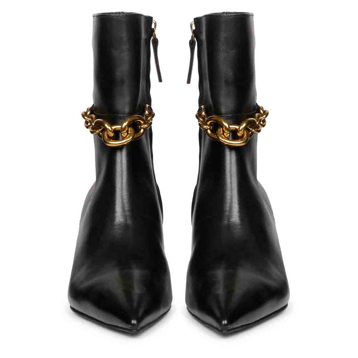 Front view of black pointed-toe ankle boots with gold chain accents at the ankle