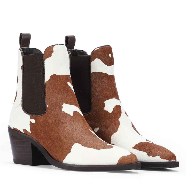 Pair of brown and white pony hair ankle boots shown from an angled side view