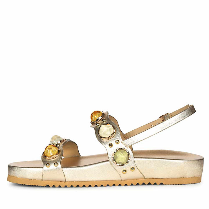 Gold sandal with gemstone embellishments on a white background