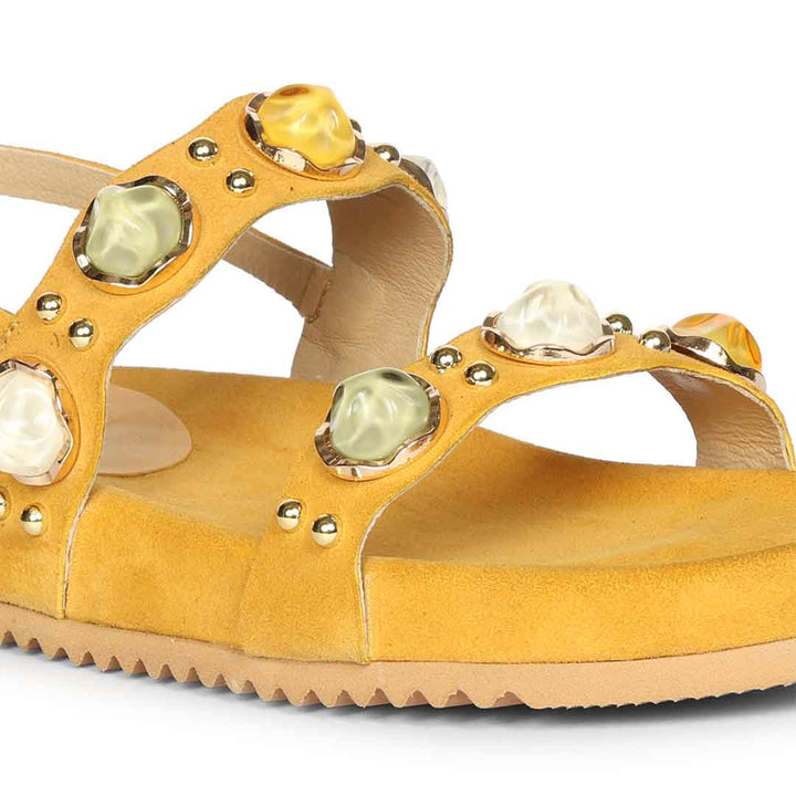 Yellow sandal with decorative stones on a white background