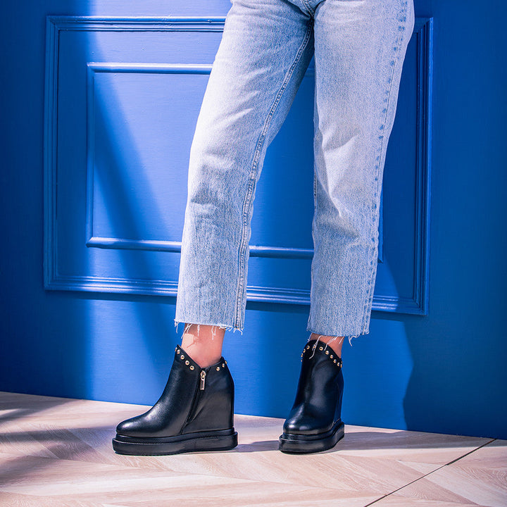 Model wearing ladies black leather wedge ankle boots with jeans