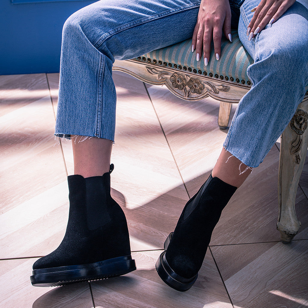 Model wearing ladies black wedge ankle boots with jeans