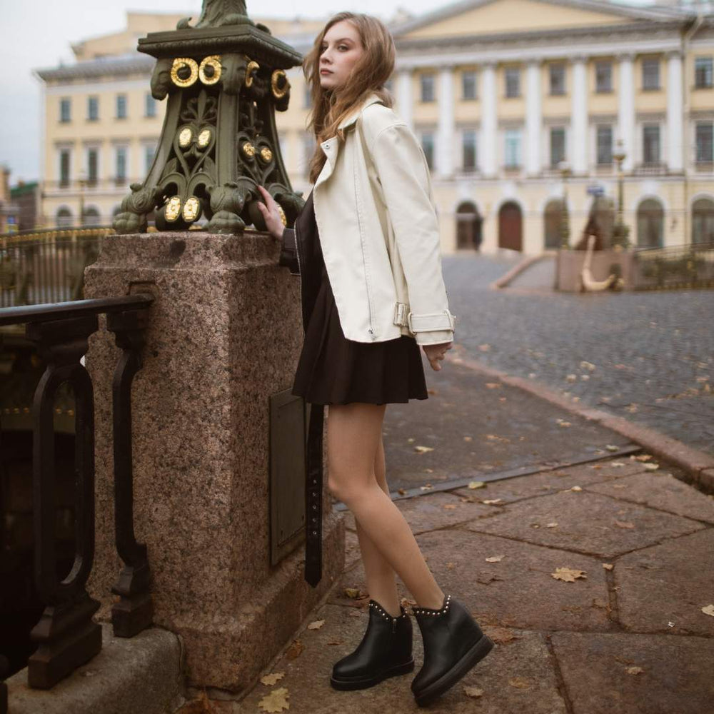 Model wearing ladies black leather wedge ankle boots, styled outdoors
