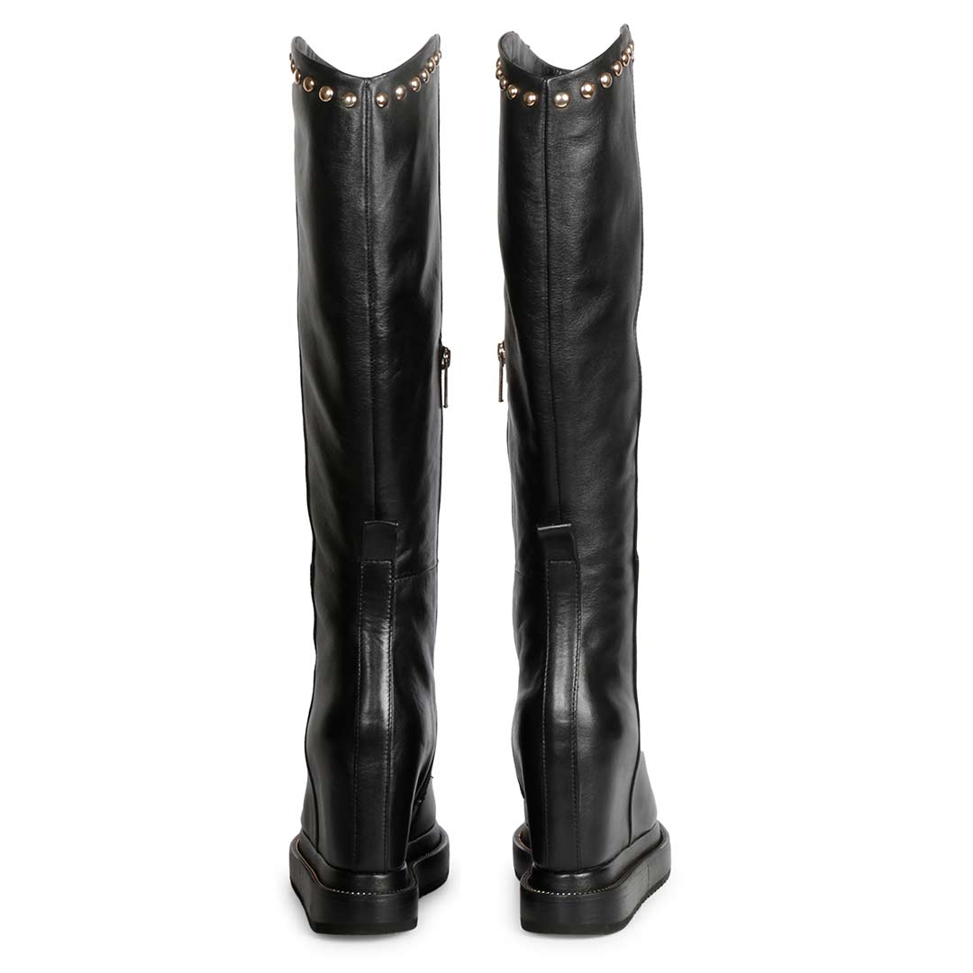 Model wearing ladies black studded leather wedge boots, styled look