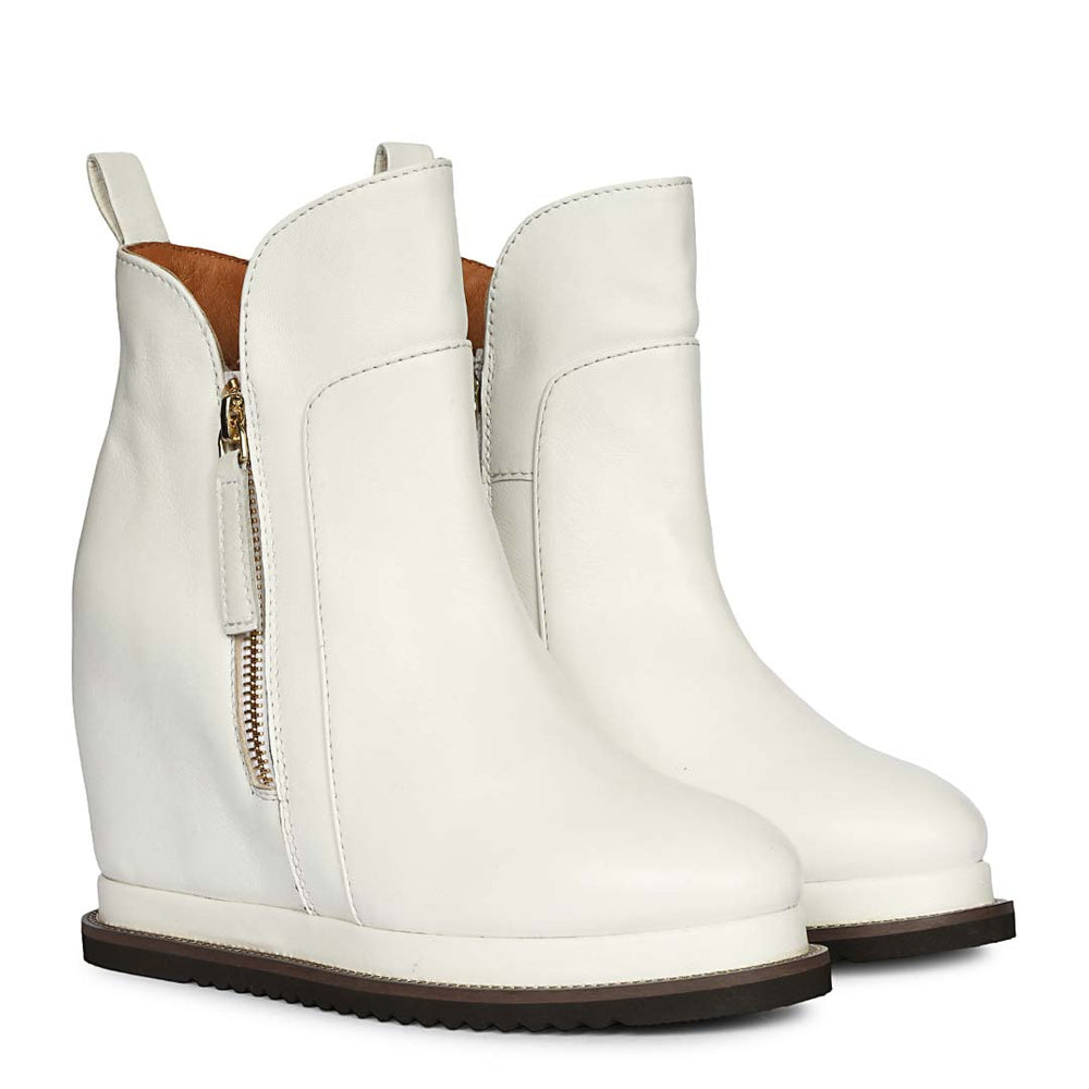 Pair of ladies white leather wedge ankle boots, angled view