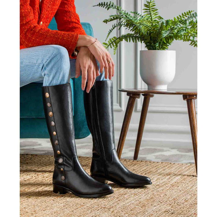 Women's black leather knee high boots by Saint Adriano, styled seated lifestyle shot