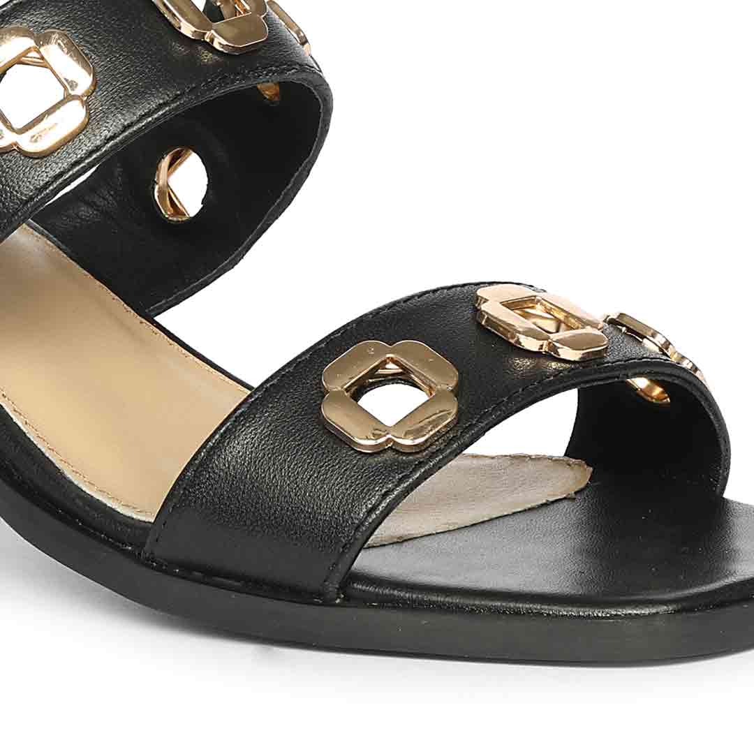 Black low block heels gold flower buckle detail – close-up