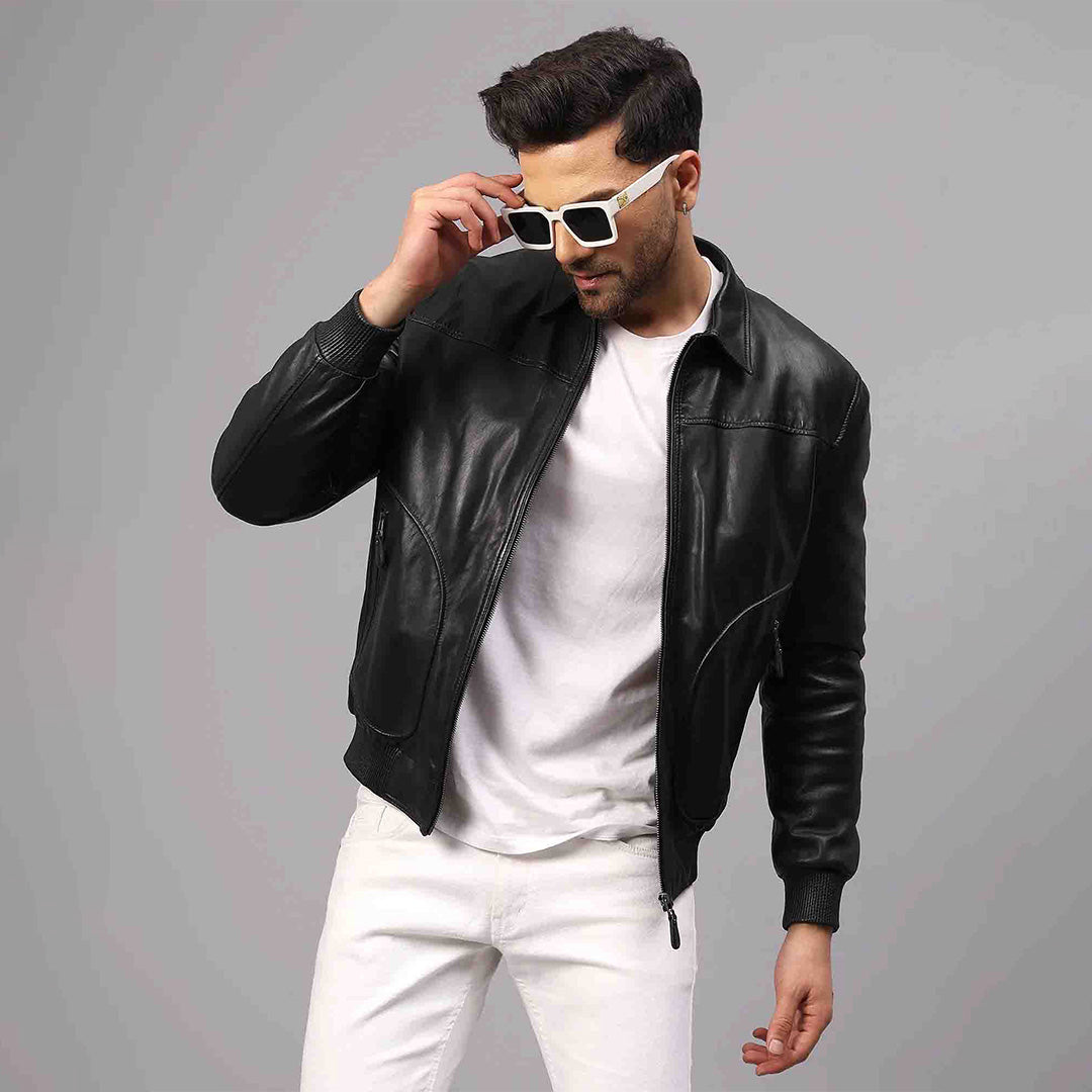 Man wearing an open black leather bomber jacket over a white t-shirt.