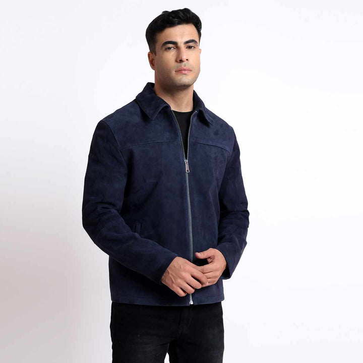 Man wearing a navy suede jacket with a shirt collar, hands clasped.