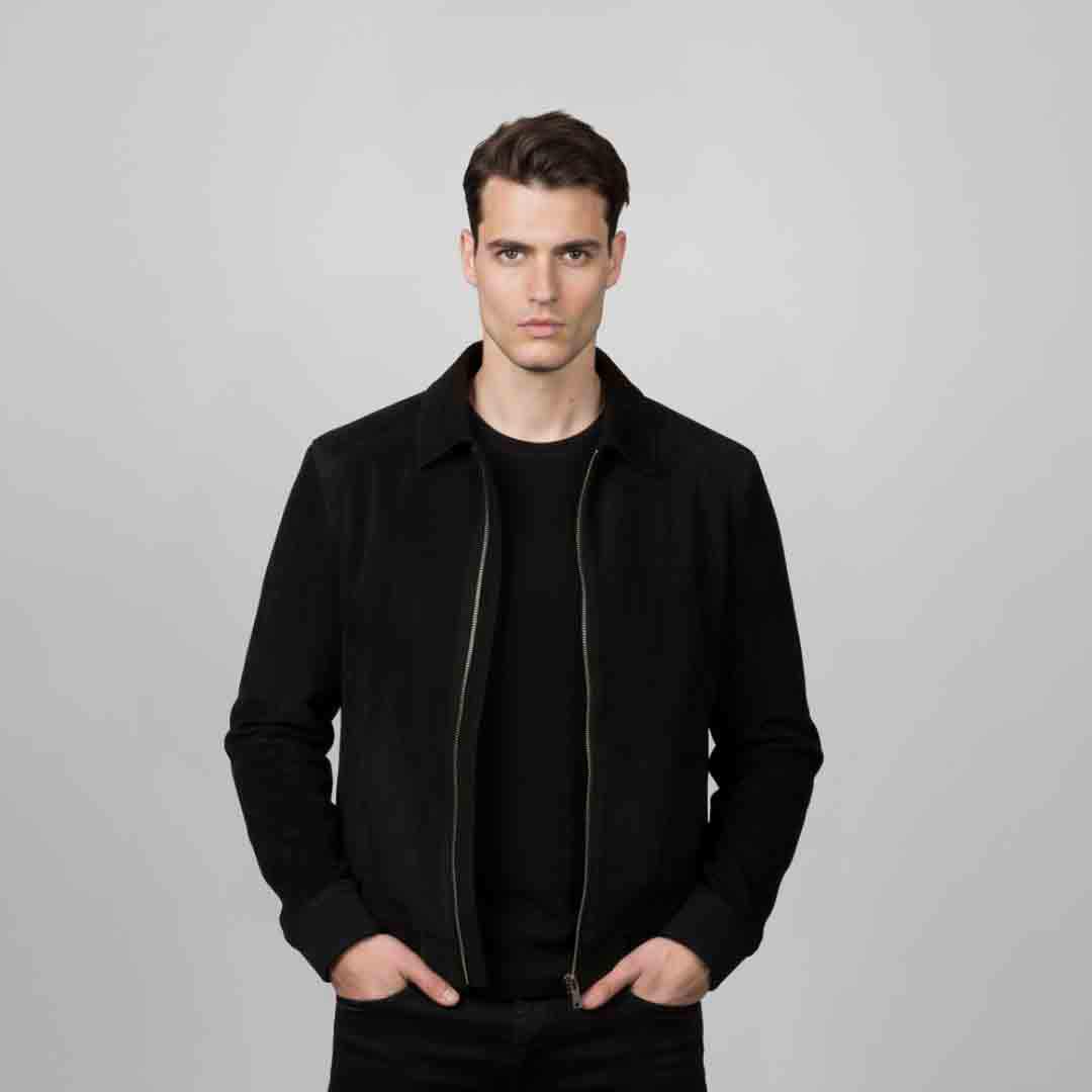 Man wearing an open black bomber jacket with fur trim.