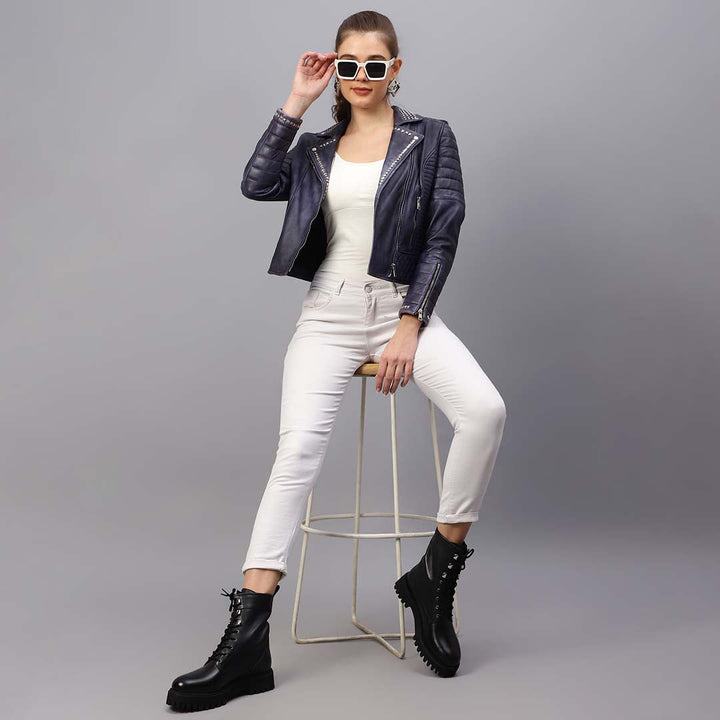 Women's blue leather biker jacket UK by Saint Brielle, styled seated lifestyle shot
