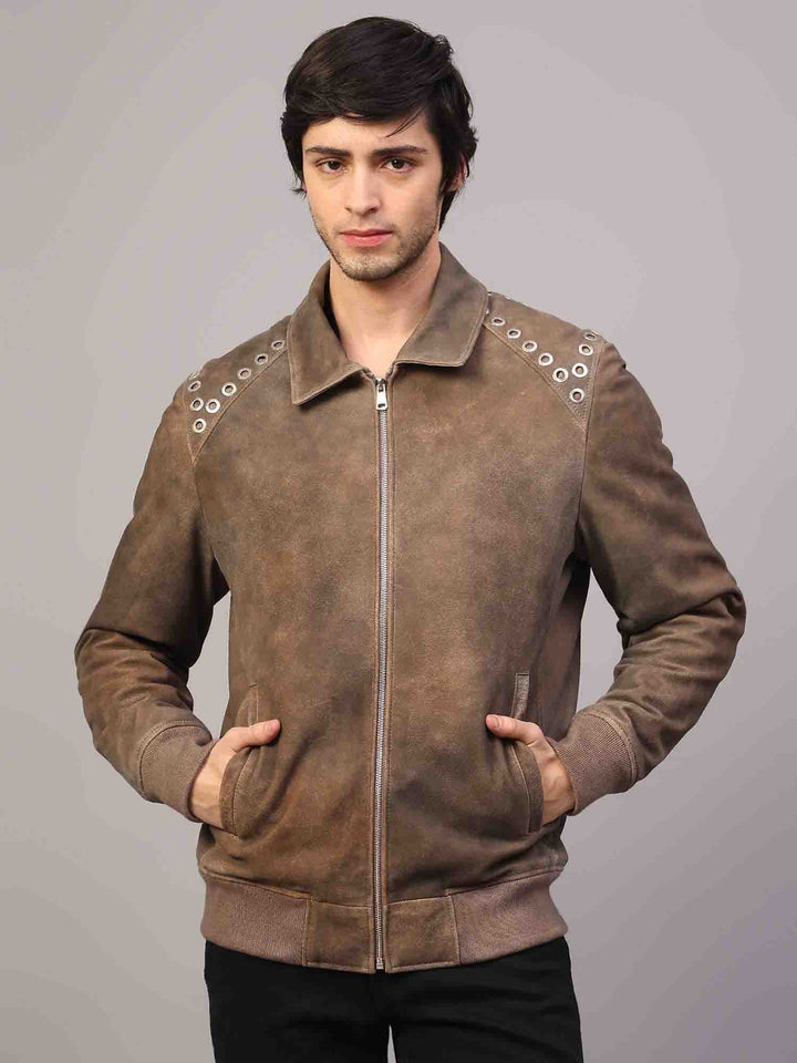 Full-length shot of a man wearing a distressed brown suede jacket with grommet hardware.