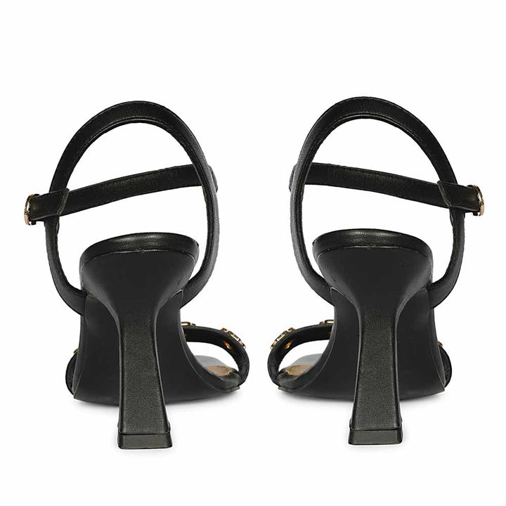 Black high-heeled shoes with thin straps on a white background, back view