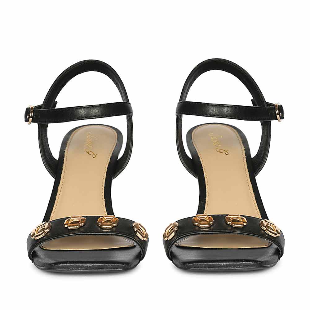 Black high-heeled sandals with gold embellishments on a white background