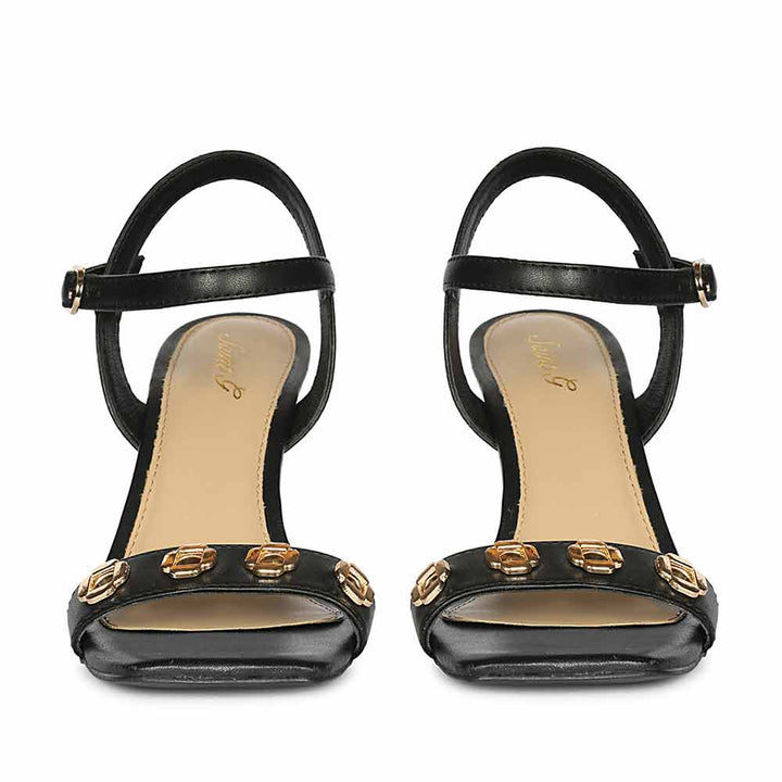 Black high-heeled sandals with gold embellishments on a white background