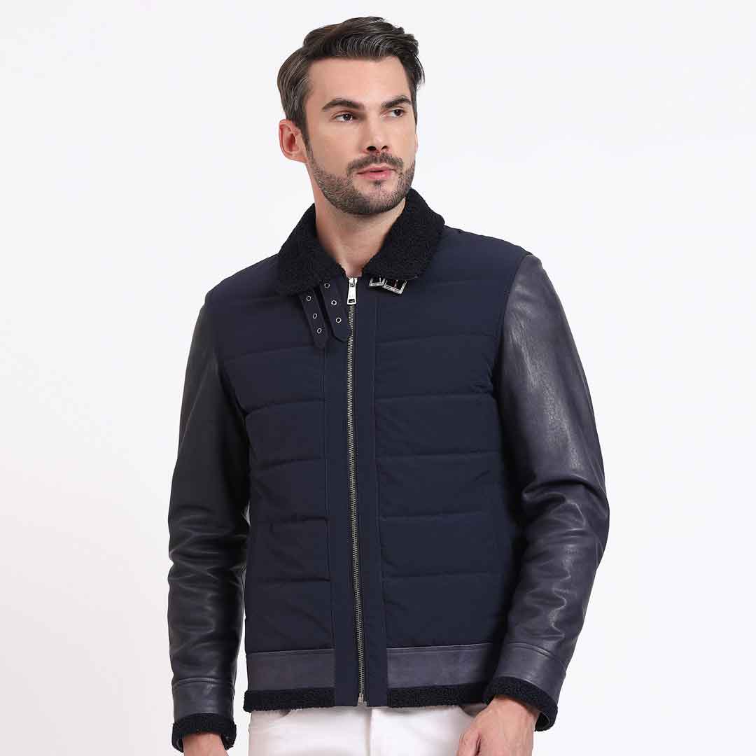 Side view of a man wearing a navy quilted jacket with black leather sleeves.
