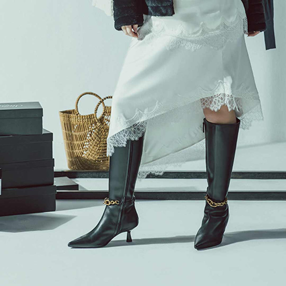 Women's black leather knee high boots by Saint Freya, styled with a lace dress, lifestyle view
