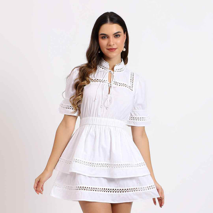 Woman wearing a solid white cotton poplin short dress with eyelet trim detailing.