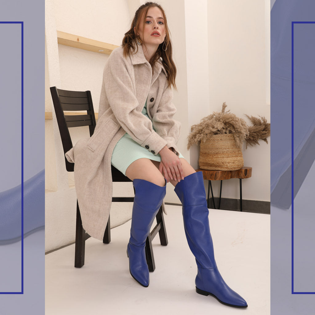Women's blue leather thigh high boots UK by Saint Grace, styled seated lifestyle shot