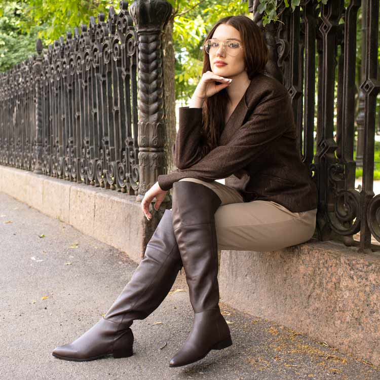 Women's brown leather above the knee boots UK by Saint Grace, styled seated lifestyle shot