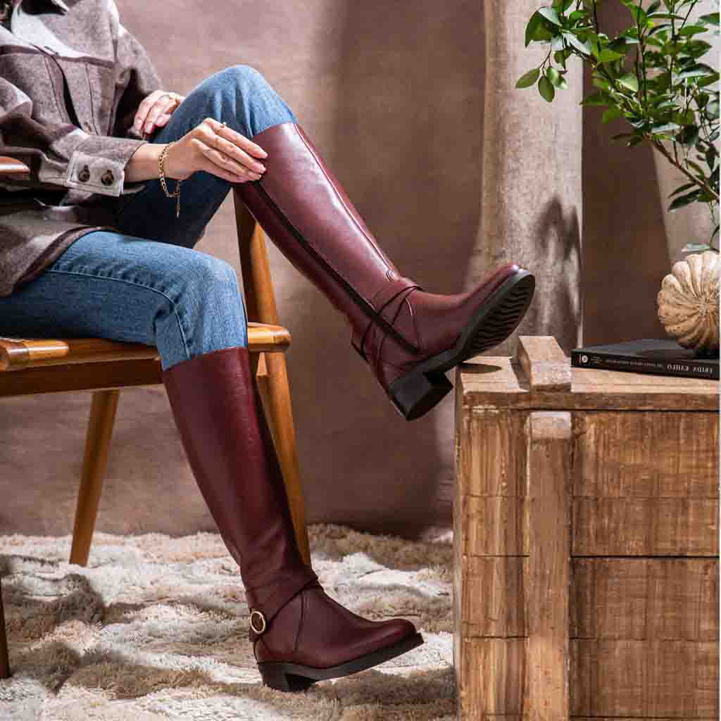 Women's teak leather knee high boots by Saint Hermione, styled seated lifestyle shot