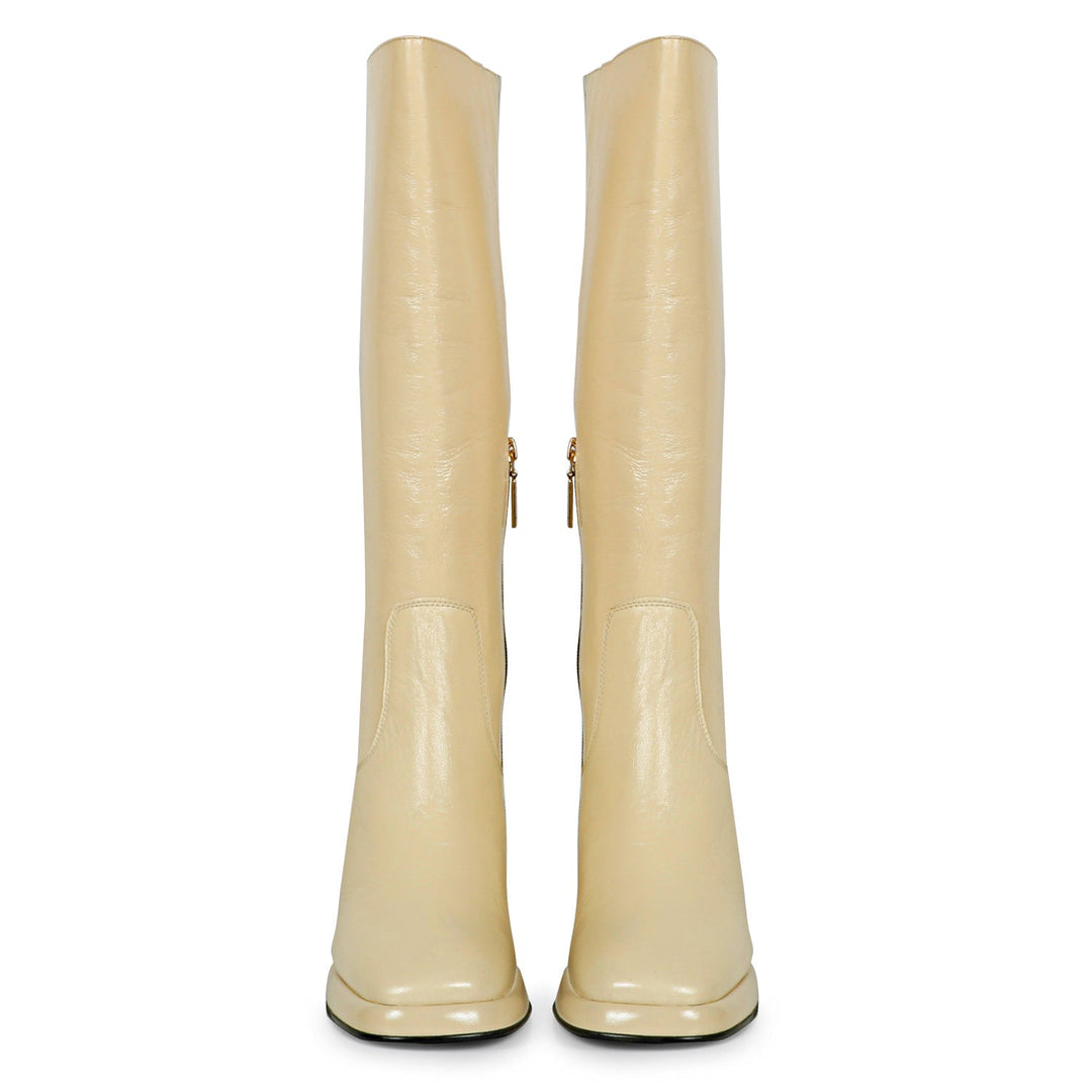 Women's off white patent leather knee high boots, front pair view