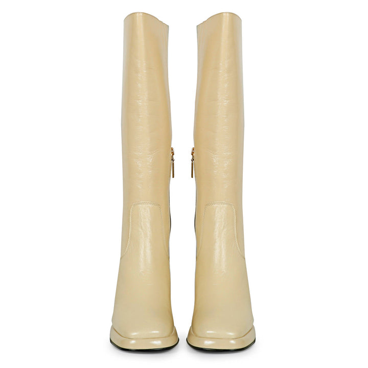 Women's off white patent leather knee high boots, front pair view