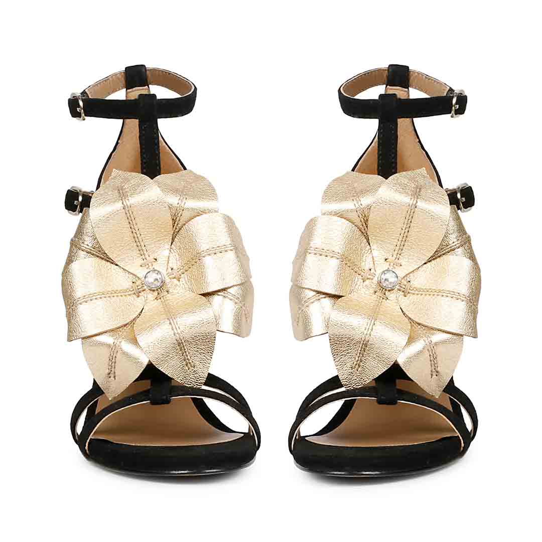 Saint Lilly gold flower embellished black leather stilettos with ankle strap detail, front view