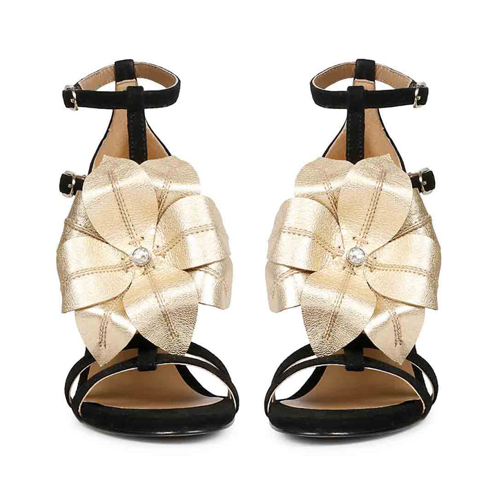 Saint Lilly gold flower embellished black leather stilettos with ankle strap detail, front view