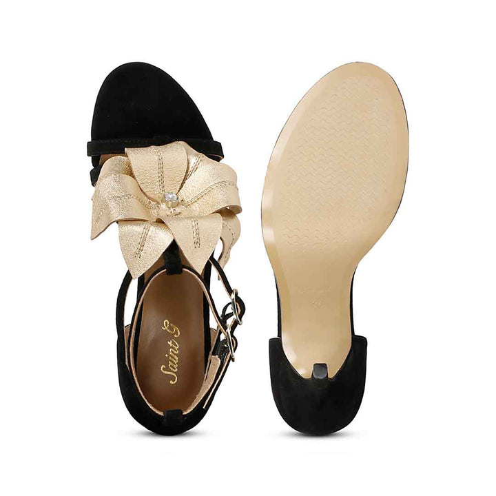 Saint Lilly gold flower embellished black leather stilettos with ankle strap detail, sole view