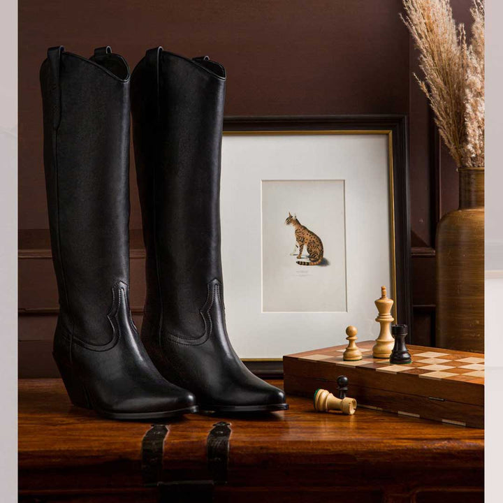 Saint Loanna black leather knee high boots, styled editorial shot with chessboard props
