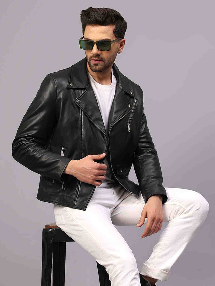 Man seated wearing a black leather biker-style jacket with an asymmetric zip.