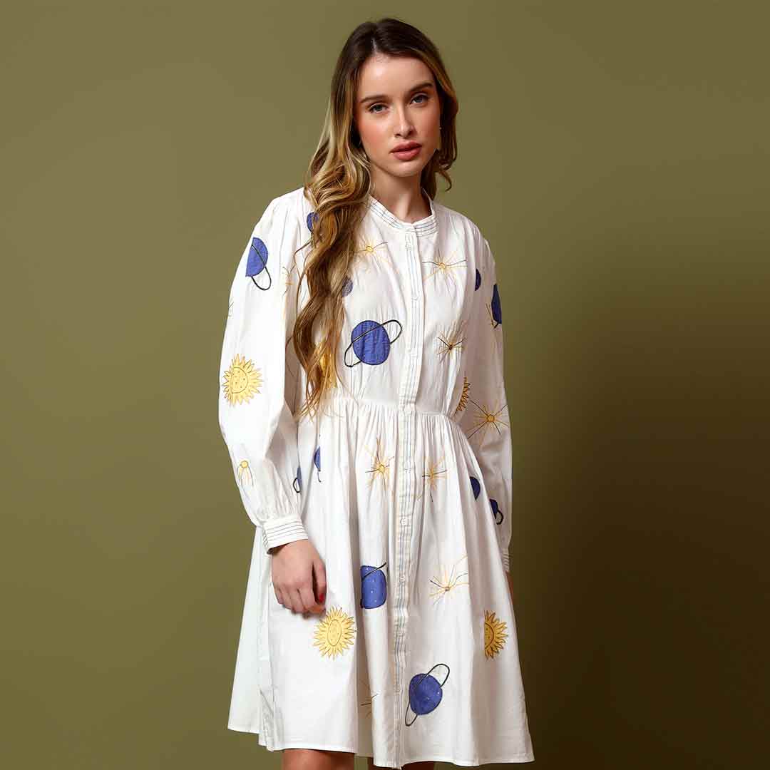 Woman wearing a white cotton poplin dress with a celestial sun and star print.