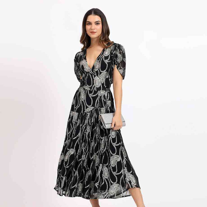 Women's black ivory paisley tea-length dress by Saint Maisie, front view styled with a clutch bag.