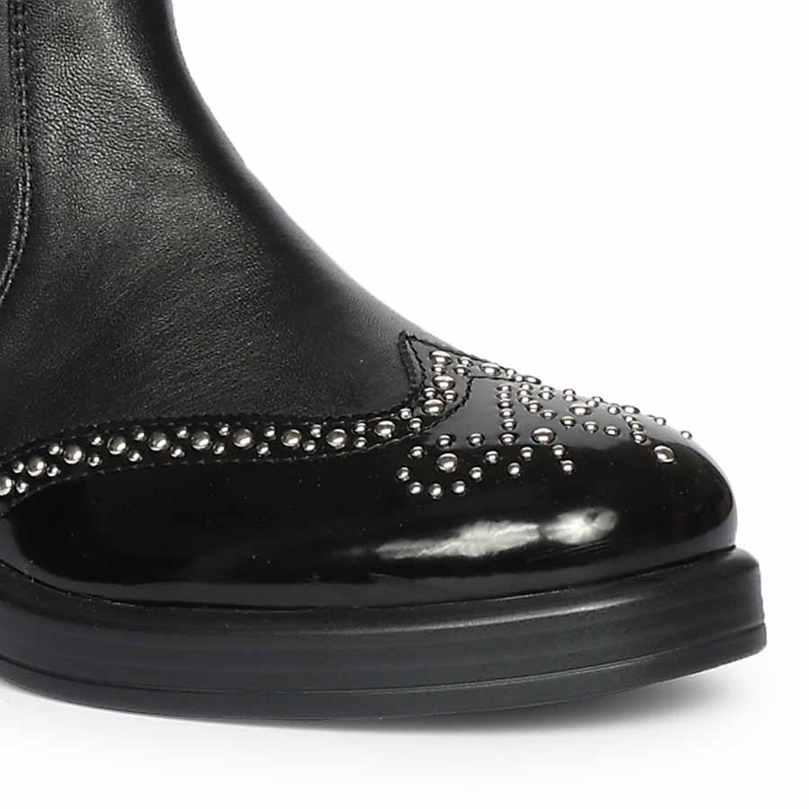 Close-up of crystal-studded patent toe cap on Saint Marcelline black leather knee high boots
