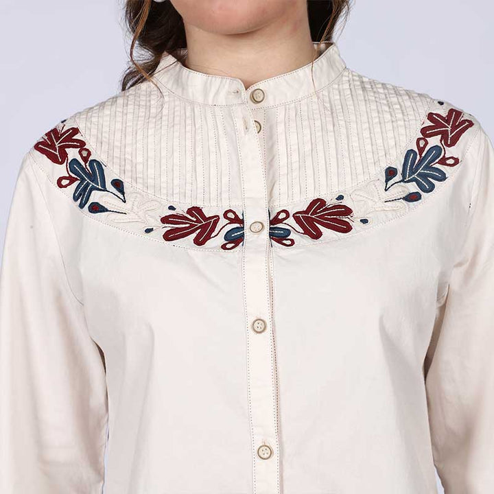 Close-up of floral embroidered pintuck yoke on Saint off-white cotton top for women UK.