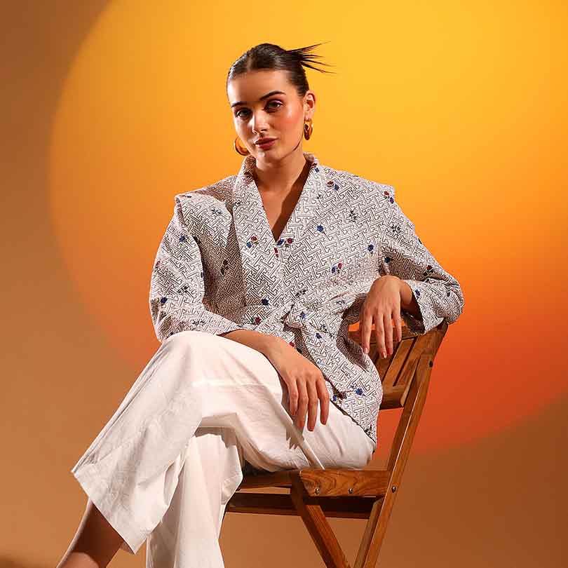 Women's beige geometric floral print wrap jacket by Saint Oriana, seated lifestyle view.