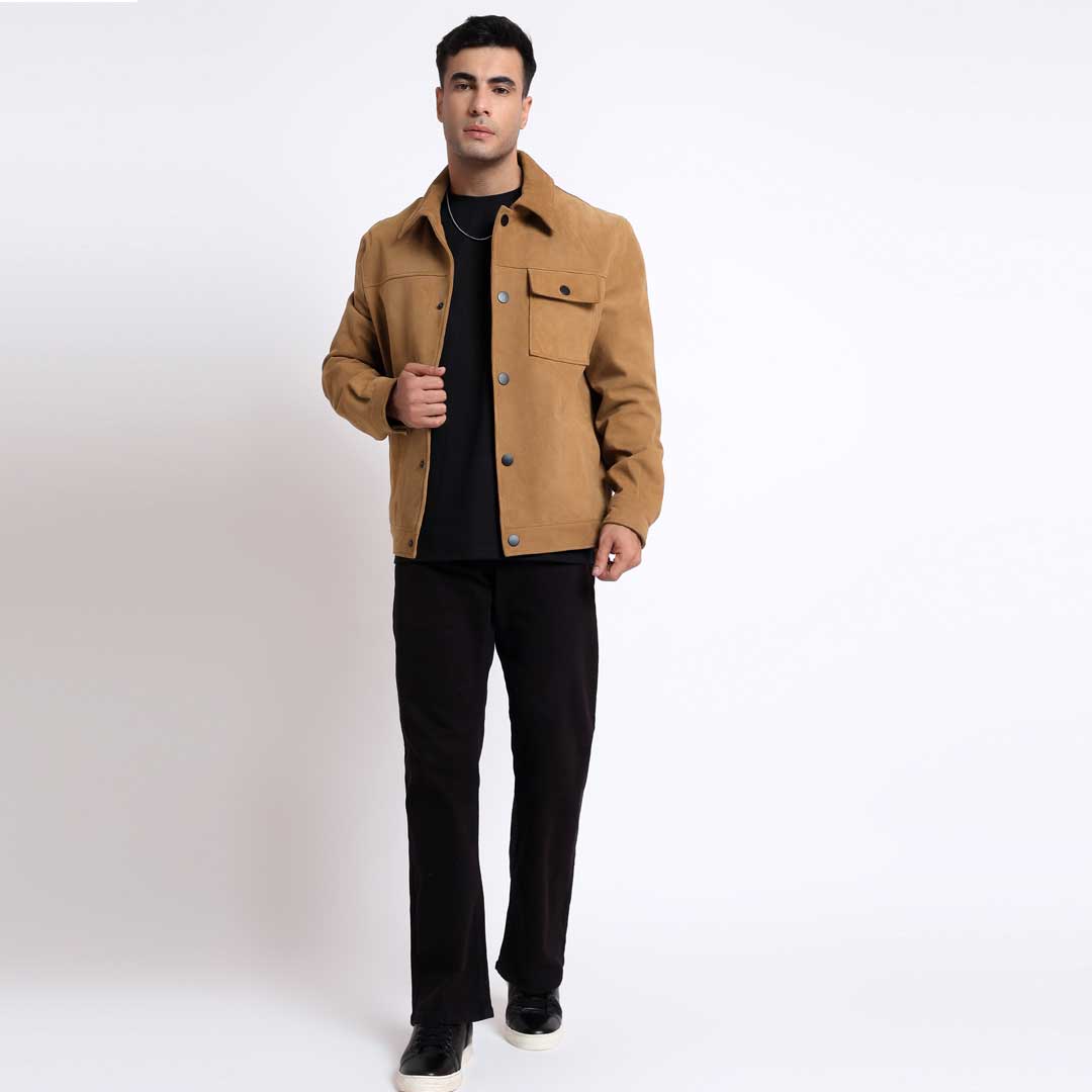 Full-length shot of a man wearing a sand suede jacket with dark trousers.