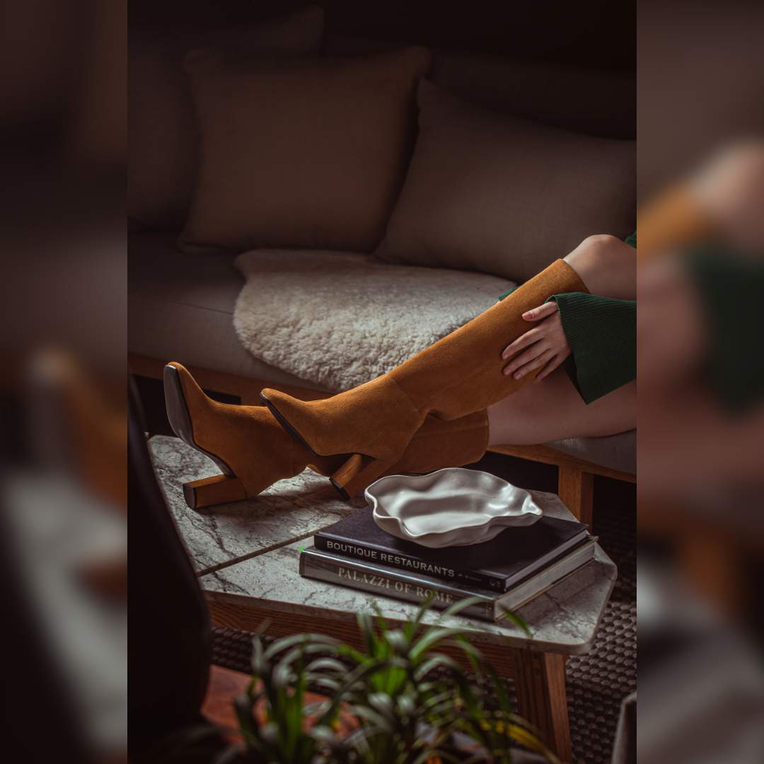 Women's tan suede slouch boots by Saint Priscilla, styled seated lifestyle shot
