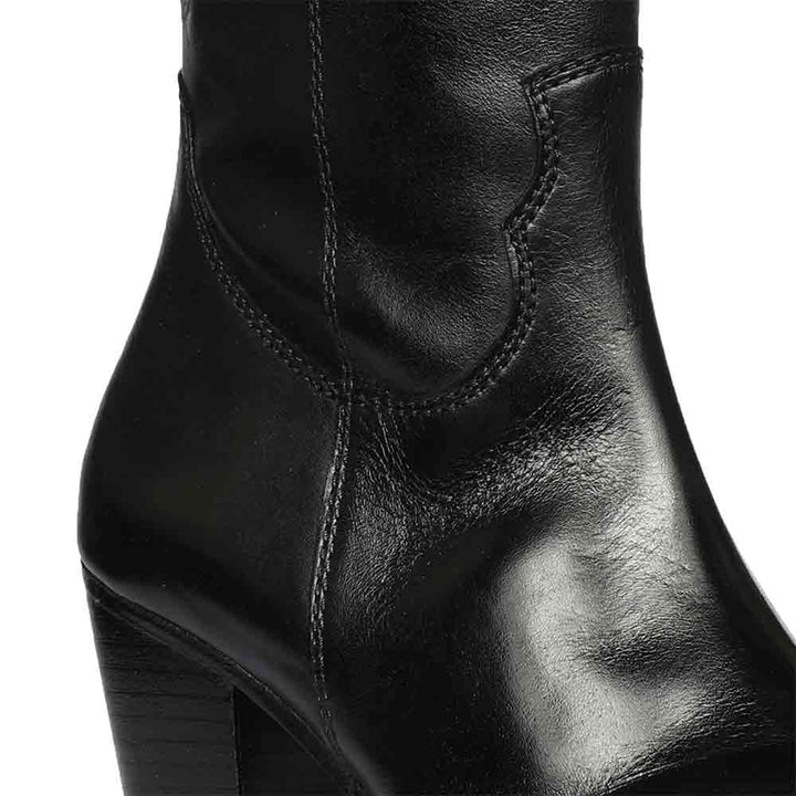 Close-up of stacked heel and western-cut shaft on Saint Prune black leather knee high boots