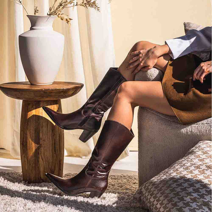 Women's brown leather knee high boots by Saint Prune, styled seated indoors, lifestyle view