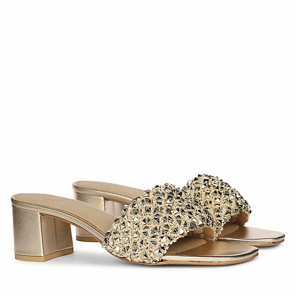 Gold low block heel sandals with embellishments on a white background