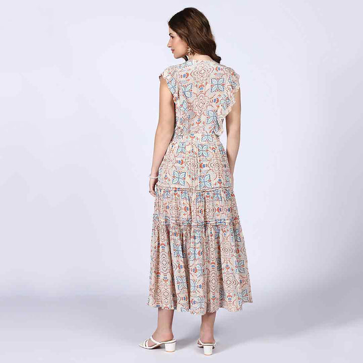 Back view of a woman wearing a beige printed tiered maxi dress.
