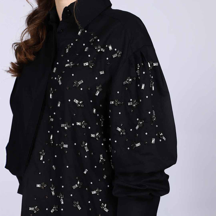 Close-up of rhinestone and pearl embellishment on a black cotton shirt collar.