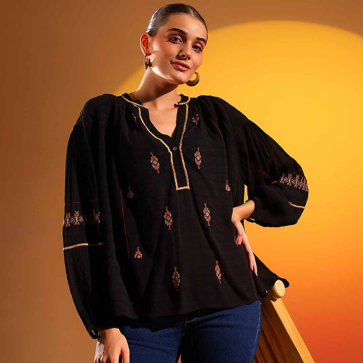 Side view of a woman wearing a black embroidered viscose top.