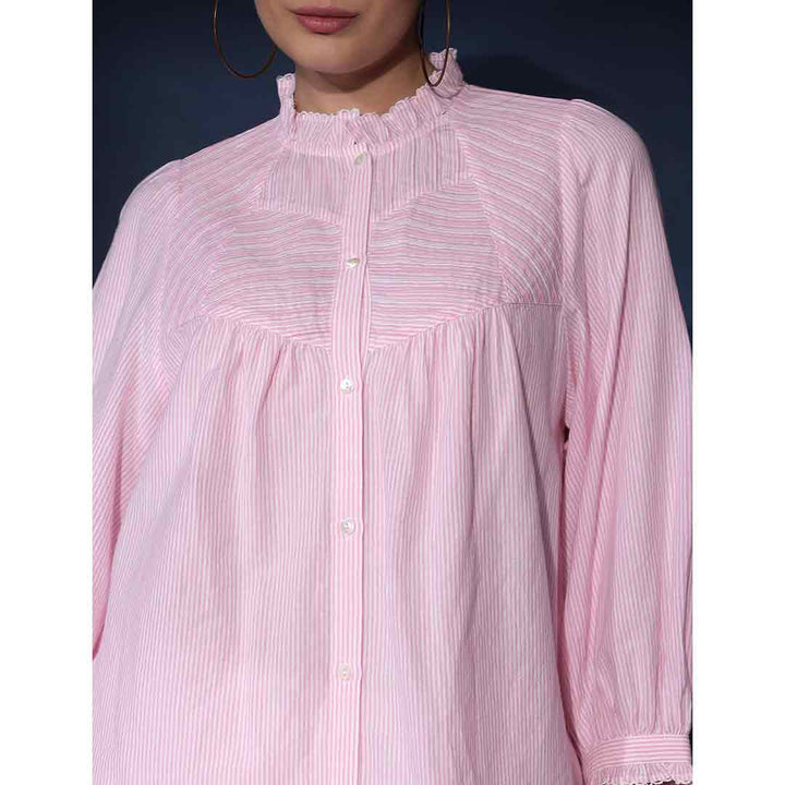 Close-up of the ruffled collar and stripe weave on a blush cotton top.