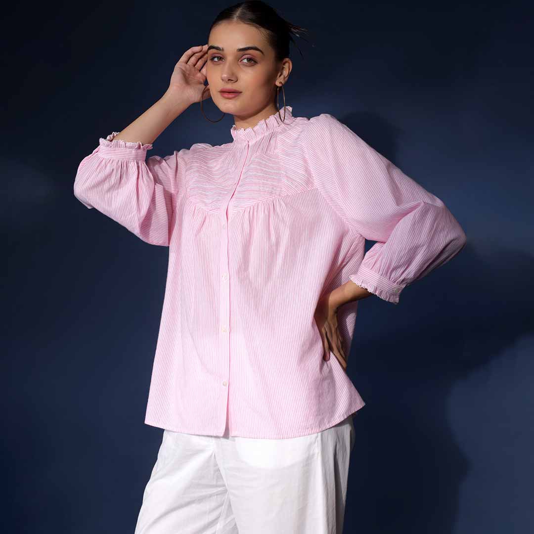 Side view of a woman wearing a blush striped cotton top with balloon sleeves.