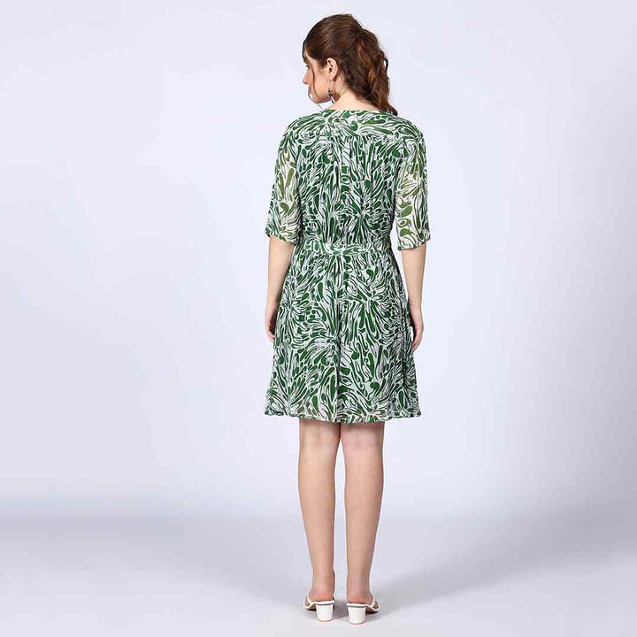 Full-length shot of a woman wearing a green and white mini dress.