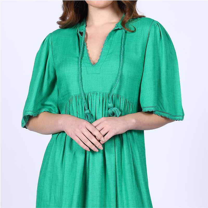 Close-up of the tasselled tie neckline on a green cotton midi dress.